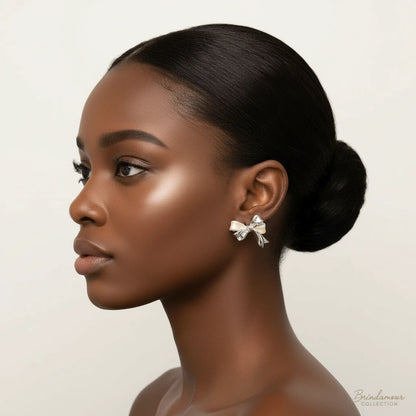 Close-up of bow-shaped stud earrings with 18K gold plated brass and silver details on white background.