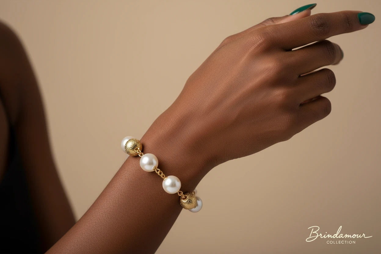 Adjustable bracelet featuring baroque pearls wrapped in gold mesh wire with delicate chain links on cream background.