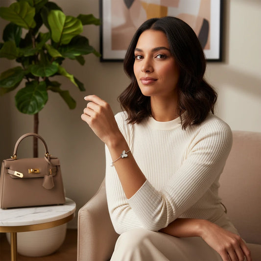 Dainty sterling silver chain bracelet with heart charm and freshwater pearl dangles on white background.