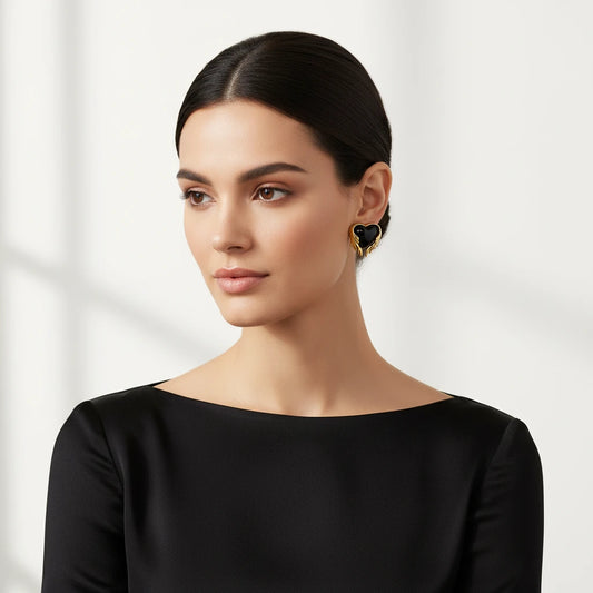 Pair of 18K gold plated earrings with wing design surrounding black resin heart centers on light background