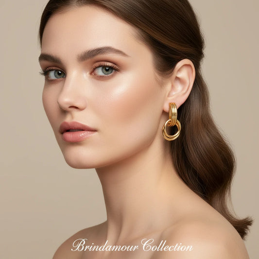 Geometric gold earrings with ribbed linear top section and circular drop elements on white background.