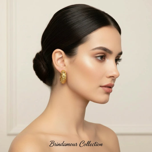 Close-up of ornate 14K gold-plated hoop earrings featuring embossed sun and star celestial motifs on neutral background.