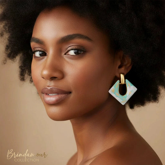 Diamond-shaped gold-plated earrings with pastel marble enamel in turquoise and lavender swirls on beige background